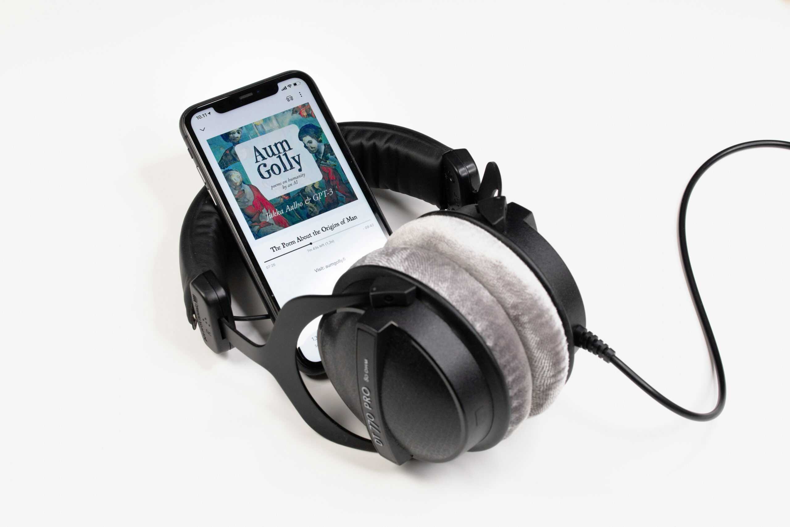Phone with audiobook on screen surrounded by headphones