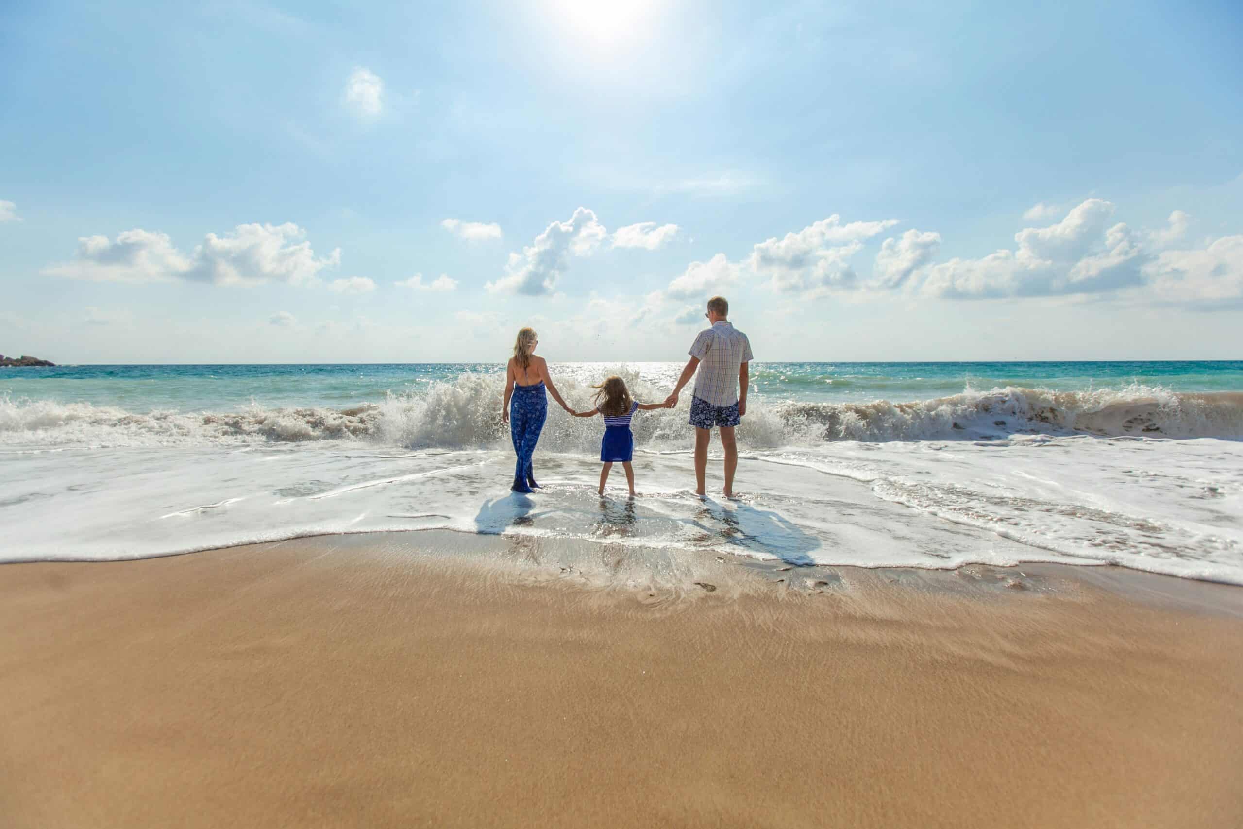 Family holding hands in water at beach vacation