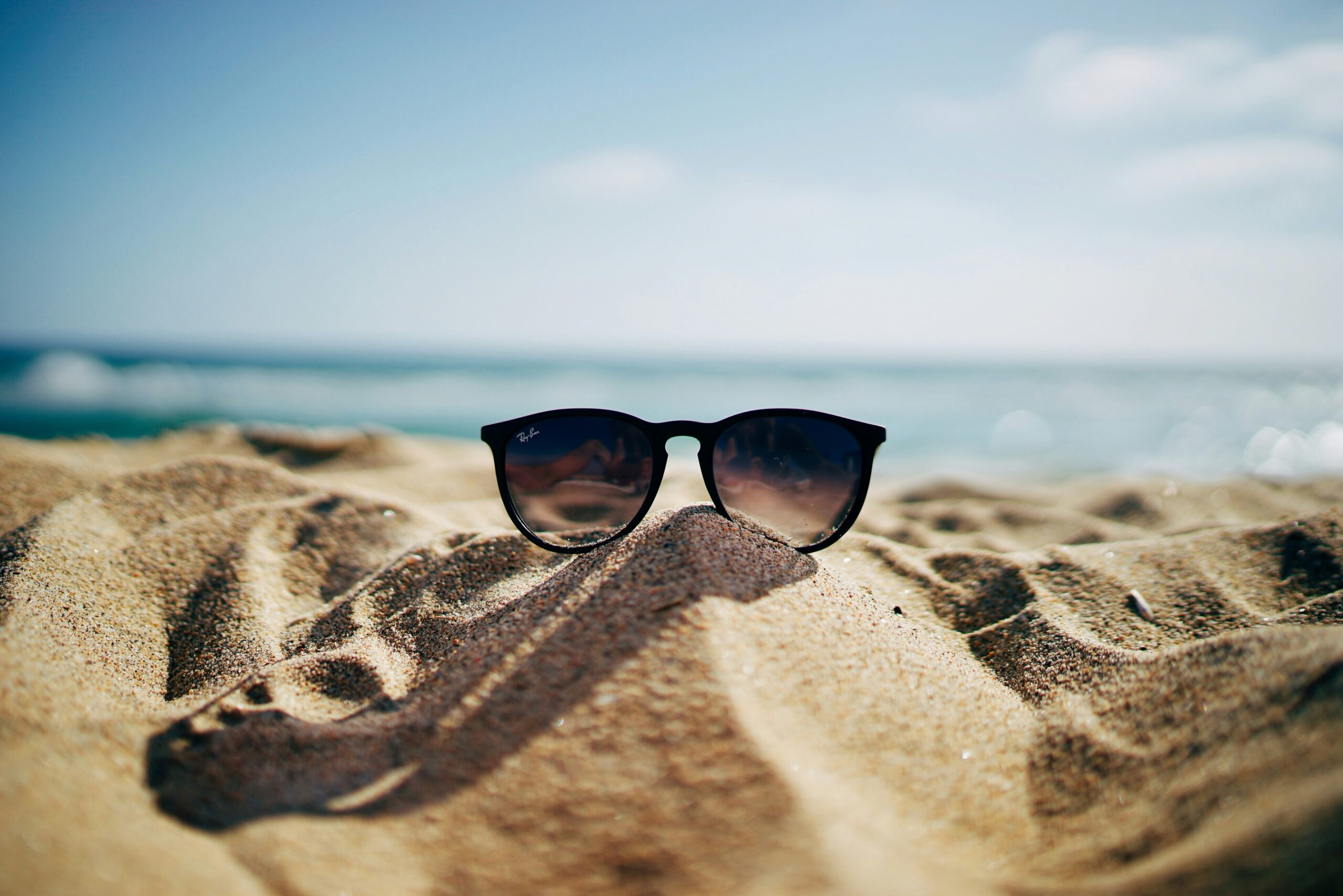 Sunglasses perched in sand on a beach