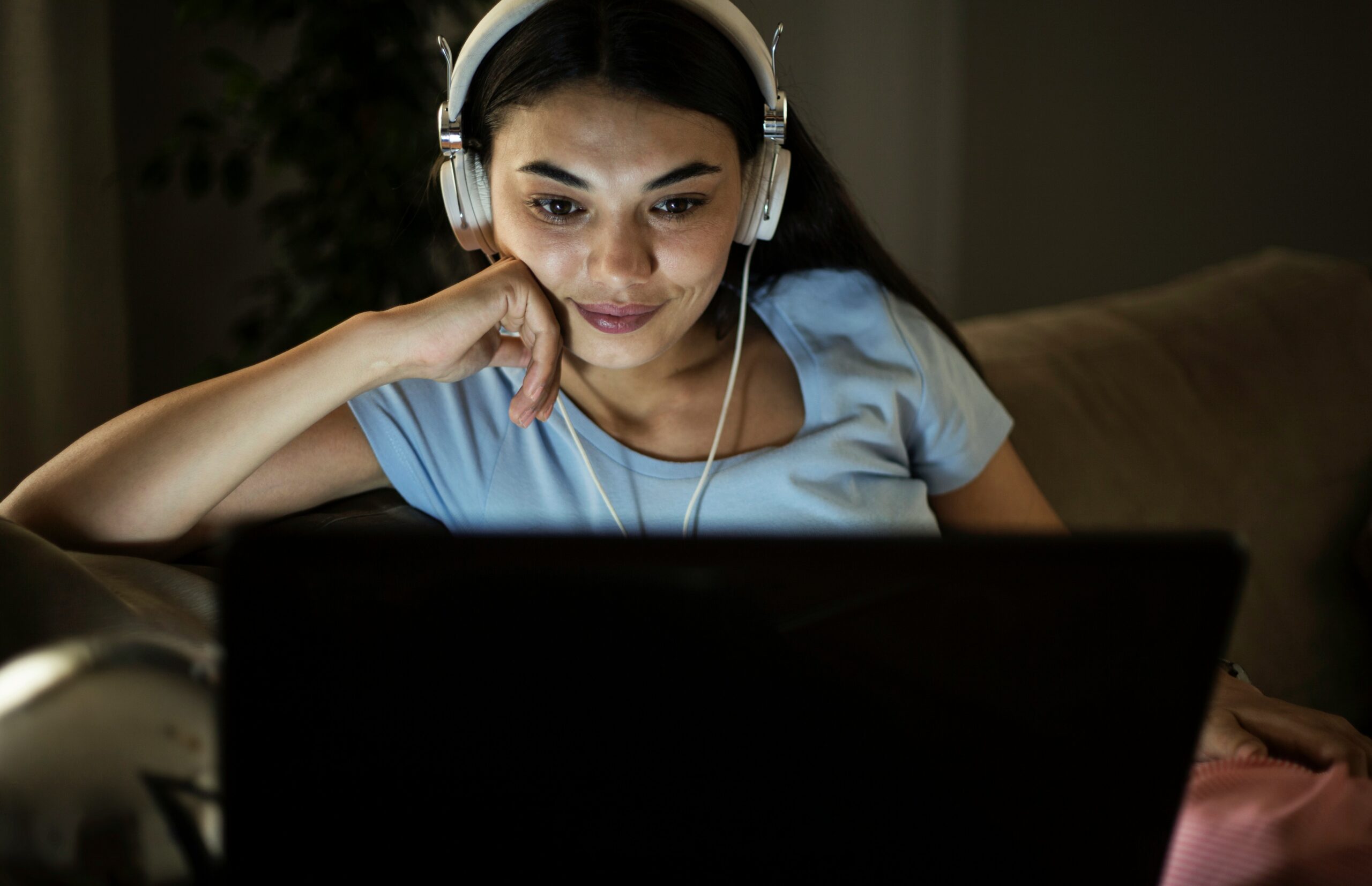 Woman wearing headphones in front of laptop at night
